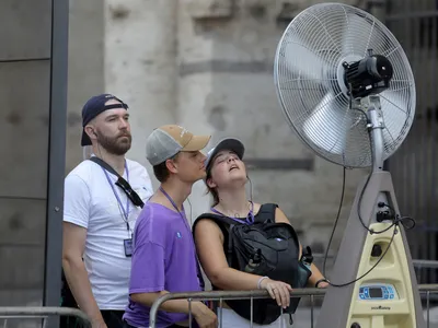 Tourists cool off in front of a fan in Rome, Italy on July 18, 2023. Temperatures in the area at the time surpassed 104 degrees Fahrenheit.