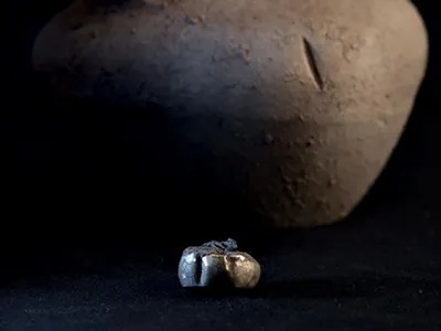 This gold earring found at an Iron Age archaeological site had been stashed inside a pottery jar, which sits behind it.